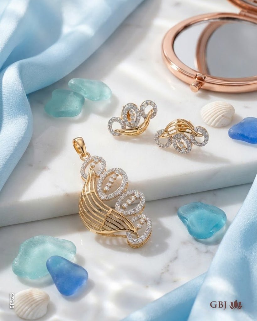 Gold and silver jewelry set featuring a seashell-shaped pendant, matching earrings, and a rose gold compact mirror, styled on a white marble slab with blue stones and satin fabric.